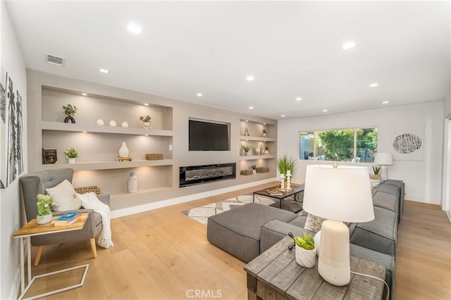 living room with light hardwood / wood-style floors and built in shelves