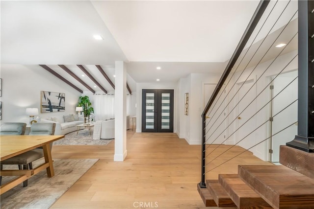 entryway with lofted ceiling with beams, light hardwood / wood-style flooring, and french doors