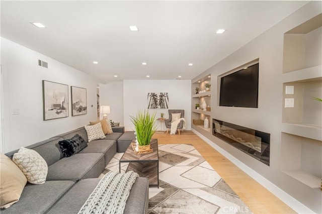 living room with light hardwood / wood-style flooring and built in shelves