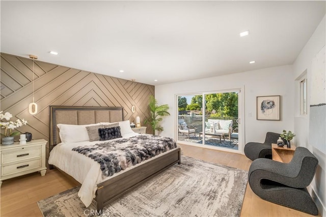 bedroom featuring access to outside, light wood-type flooring, and wood walls