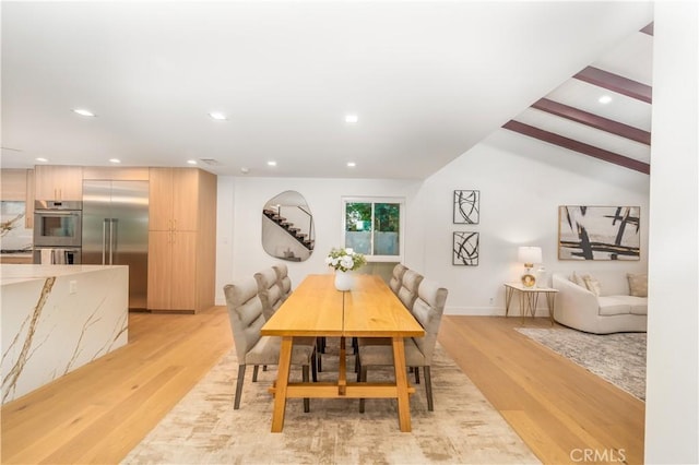 dining area featuring lofted ceiling with beams and light wood-type flooring