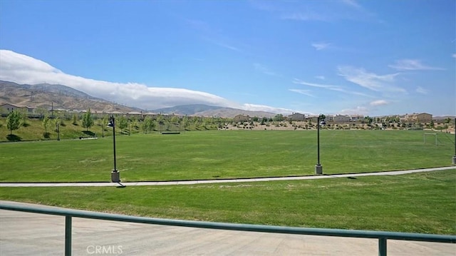 surrounding community with a mountain view and a lawn