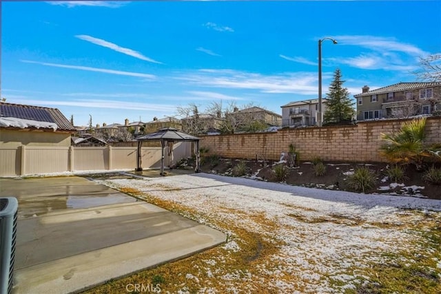 yard covered in snow with a gazebo and a patio