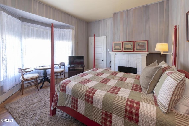 bedroom with hardwood / wood-style floors and a brick fireplace