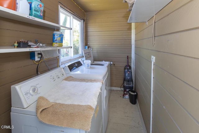 clothes washing area with wooden walls and washing machine and dryer