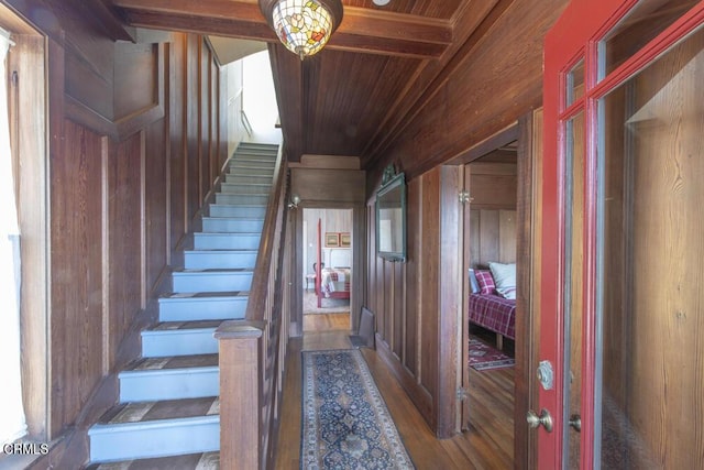 stairs featuring beam ceiling, hardwood / wood-style floors, wood ceiling, and wood walls