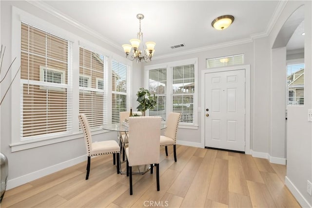 dining space with ornamental molding, light hardwood / wood-style flooring, and a notable chandelier