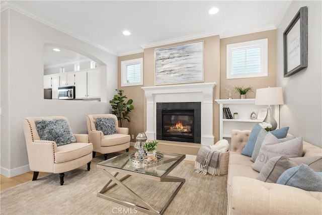 sitting room featuring a tile fireplace, ornamental molding, and light wood-type flooring