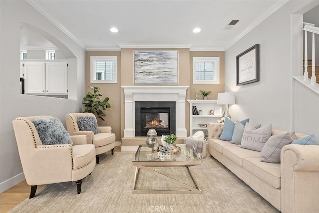 living room with a tile fireplace, wood-type flooring, ornamental molding, and a wealth of natural light