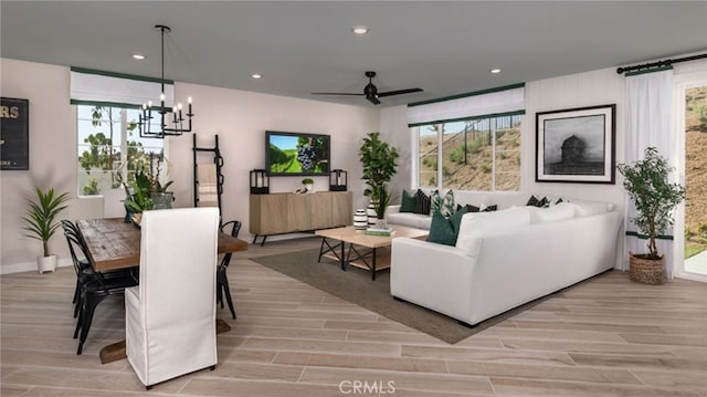 living room with plenty of natural light, ceiling fan with notable chandelier, and light hardwood / wood-style flooring