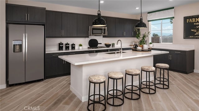 kitchen with stainless steel appliances, a center island with sink, pendant lighting, and a kitchen breakfast bar