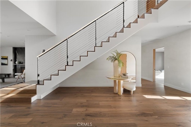 staircase with a towering ceiling and hardwood / wood-style floors