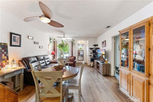 dining room with ceiling fan, hardwood / wood-style floors, and a textured ceiling