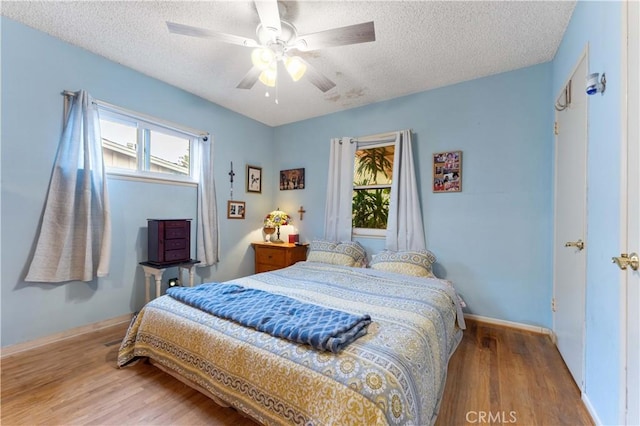 bedroom with hardwood / wood-style flooring, multiple windows, and a textured ceiling