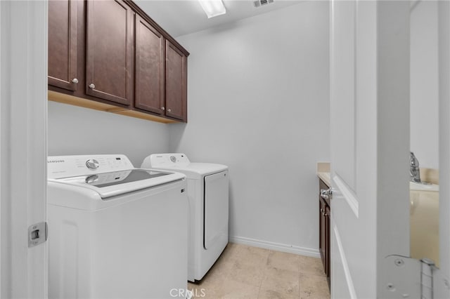 clothes washing area with cabinets and washer and dryer