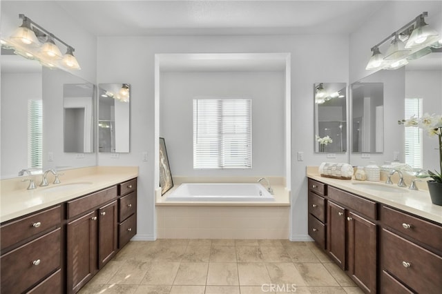 bathroom featuring a garden tub, two vanities, and a sink