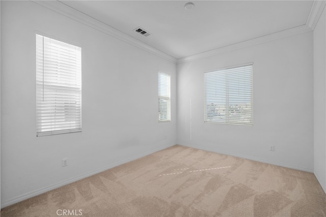 spare room featuring light carpet, baseboards, visible vents, and crown molding