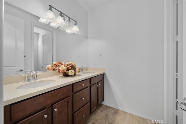 bathroom featuring double vanity, a sink, and baseboards