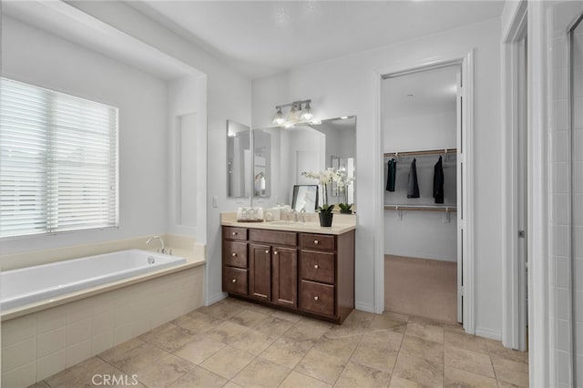 full bathroom with a bath, a walk in closet, and vanity