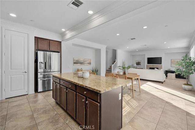 kitchen with visible vents, dark brown cabinetry, a kitchen island, light stone countertops, and stainless steel fridge with ice dispenser