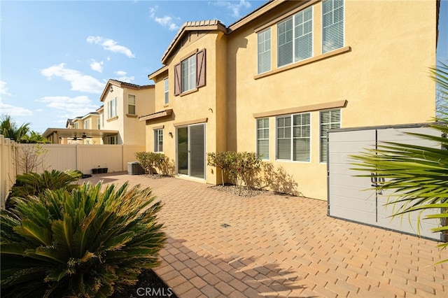 back of property with central air condition unit, a patio area, fence, and stucco siding