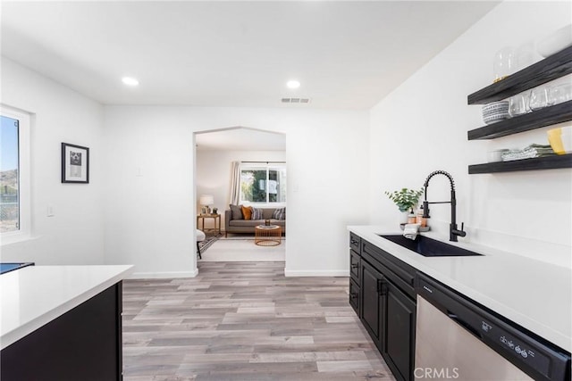 kitchen with sink, stainless steel dishwasher, and light hardwood / wood-style flooring