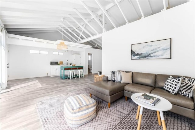 living room with hardwood / wood-style flooring, sink, and high vaulted ceiling