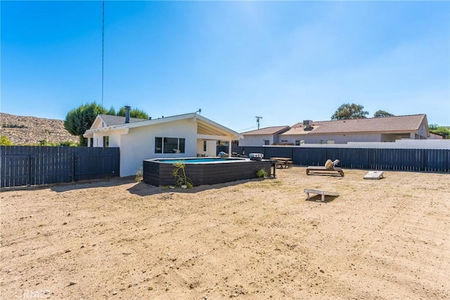 back of property with a fenced in pool