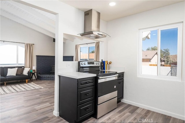 kitchen with island exhaust hood, lofted ceiling, stainless steel range with electric cooktop, and a wealth of natural light