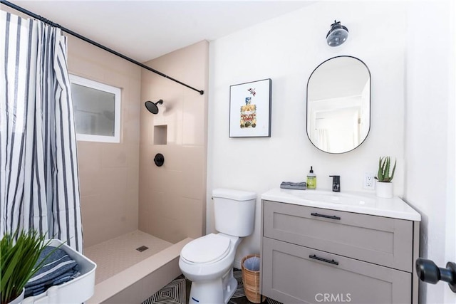 bathroom with vanity, toilet, and a tile shower