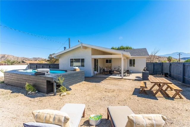 rear view of house with a mountain view, a patio, and a fenced in pool