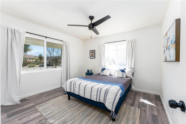 bedroom featuring multiple windows, dark wood-type flooring, and ceiling fan