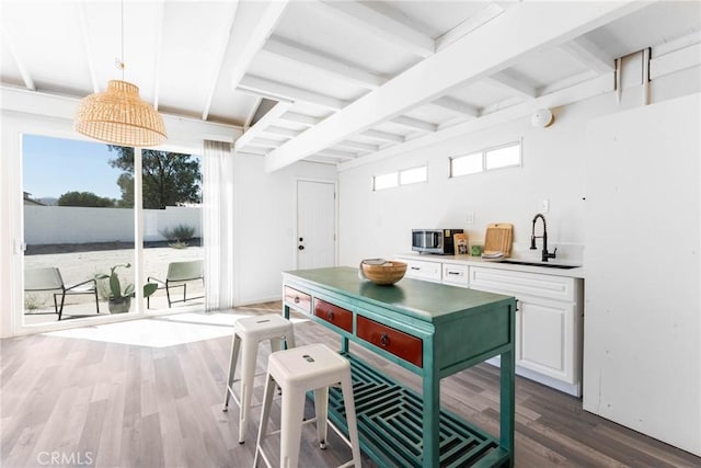 kitchen with sink, hanging light fixtures, dark hardwood / wood-style floors, white cabinets, and beamed ceiling