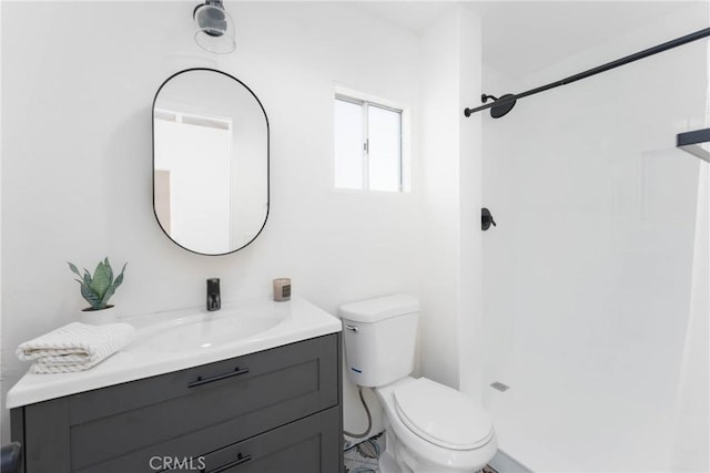 bathroom featuring vanity, walk in shower, and toilet