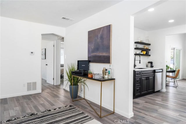 bar featuring dishwasher, sink, and light hardwood / wood-style floors