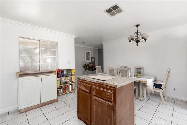 kitchen with light tile patterned floors, a kitchen island, visible vents, and a chandelier