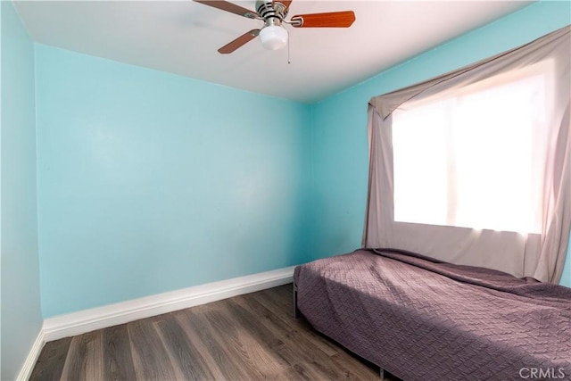 bedroom with dark wood finished floors, a ceiling fan, and baseboards