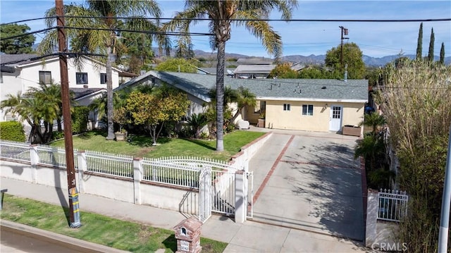 view of front of house with a fenced front yard, a mountain view, driveway, a gate, and stucco siding