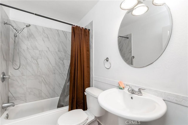 bathroom with toilet, shower / tub combo, and a sink