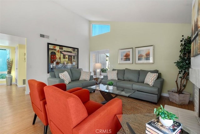 living room with high vaulted ceiling and light hardwood / wood-style flooring