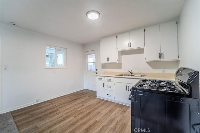 kitchen featuring light wood-type flooring, black range with gas stovetop, sink, and white cabinets