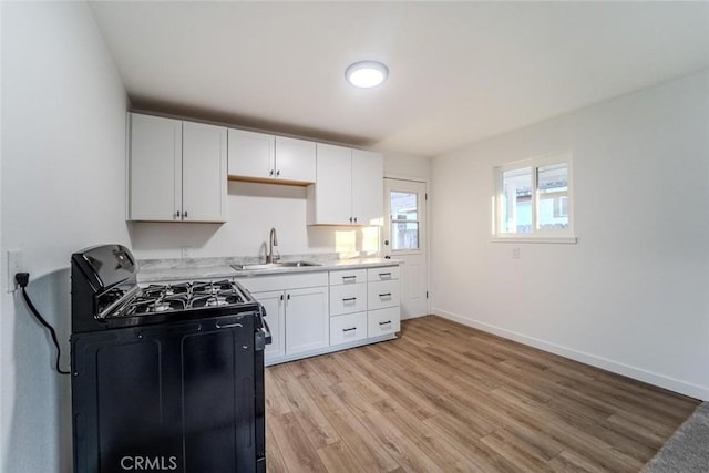 kitchen with white cabinetry, sink, light hardwood / wood-style floors, and gas stove