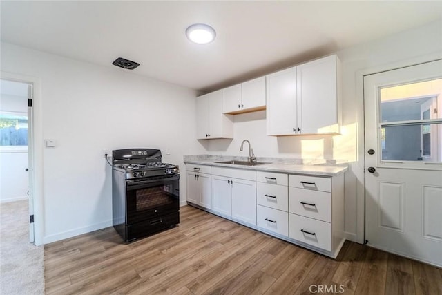 kitchen featuring gas stove, sink, white cabinets, and light hardwood / wood-style flooring