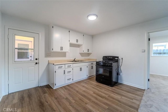 kitchen with black range with gas stovetop, light hardwood / wood-style floors, sink, and white cabinets