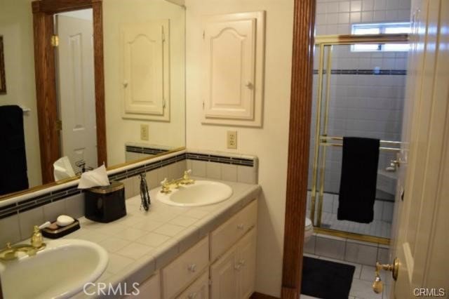 bathroom featuring vanity, radiator heating unit, a shower with door, and backsplash