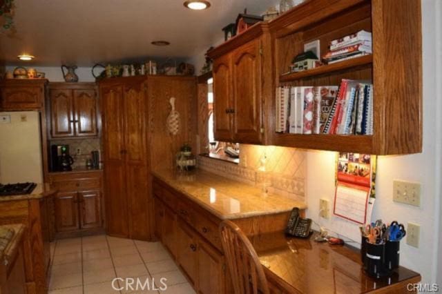 kitchen featuring tasteful backsplash, light tile patterned floors, and refrigerator