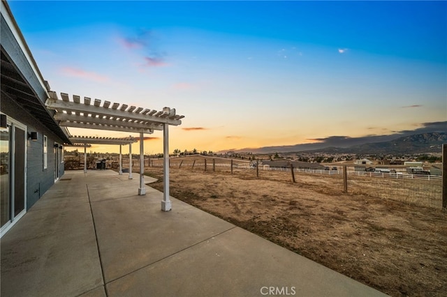 yard at dusk with a patio, a mountain view, and a pergola