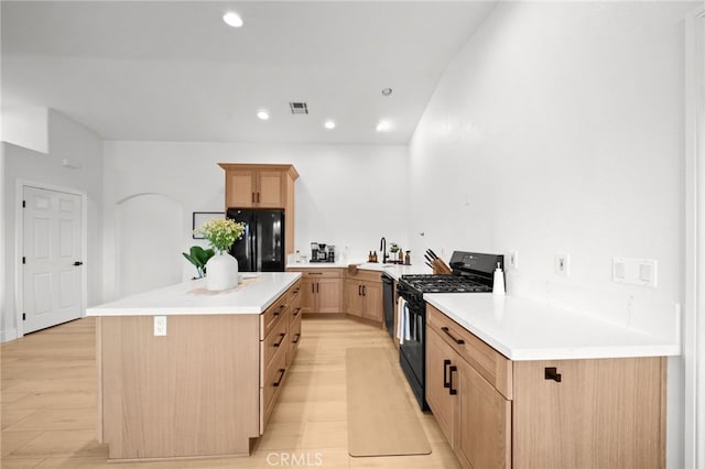 kitchen with sink, light brown cabinets, kitchen peninsula, a kitchen island, and black appliances