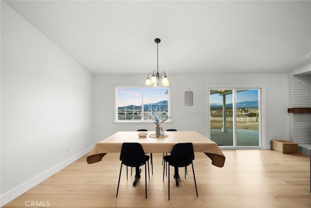 dining space featuring a mountain view, a wealth of natural light, an inviting chandelier, and light hardwood / wood-style floors