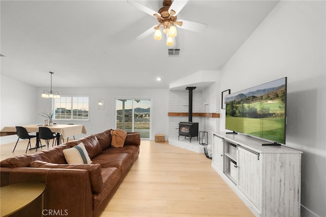 living room featuring ceiling fan with notable chandelier, light hardwood / wood-style flooring, and a wood stove